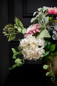 Plastic handmade bouquet artificial flowers composition.Beautiful flowers in vase on a table with black  background. Women's, mother's day. Spring, summer season. Front view.Selective focus.
