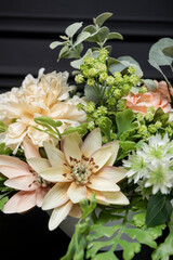 Plastic handmade bouquet artificial flowers composition.Beautiful flowers in vase on a table with black  background. Women's, mother's day. Spring, summer season. Front view.Selective focus.
