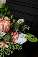 Plastic handmade bouquet artificial flowers composition.Beautiful flowers in vase on a table with black  background. Women's, mother's day. Spring, summer season. Front view.Selective focus.
