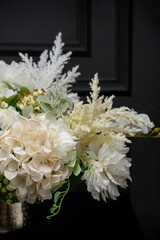 Plastic handmade bouquet artificial flowers composition.Beautiful flowers in vase on a table with black  background. Women's, mother's day. Spring, summer season. Front view.Selective focus.
