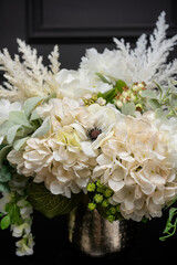 Plastic handmade bouquet artificial flowers composition.Beautiful flowers in vase on a table with black  background. Women's, mother's day. Spring, summer season. Front view.Selective focus.
