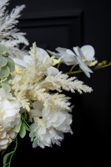 Plastic handmade bouquet artificial flowers composition.Beautiful flowers in vase on a table with black  background. Women's, mother's day. Spring, summer season. Front view.Selective focus.

