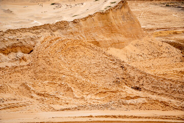 Textural sand, with  relief surface, multi-colored layers and different in size of granules, in outdoor sand career, after mining ore and sand for construction.