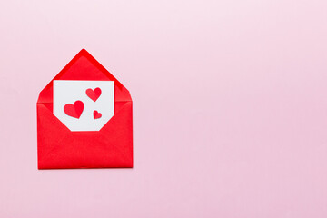 Red paper envelope with empty white card and heart on colored background. top view valentines day concept