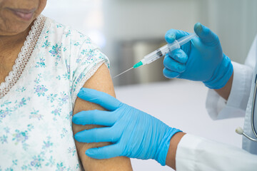 Elderly Asian senior woman wearing face mask getting covid-19 or coronavirus vaccine by doctor make injection.
