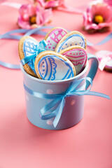 Blue mug with easter cookies on pink background