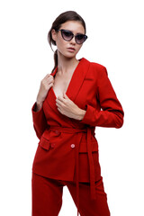 High fashion photo of a beautiful elegant young woman in a pretty red suit, jacket, pants, trousers and sunglasses posing over white background. Slim figure. Studio Shot. Businesswoman