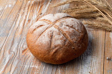 Appetizing round loaf of rye bread on wooden table, rustic style photo with copy space