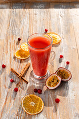 Hot berry tea with maracuja and raspberry, transparent glass with pink liquid, ingredients around