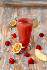 Hot berry tea with maracuja and raspberry, transparent glass with pink liquid, ingredients around