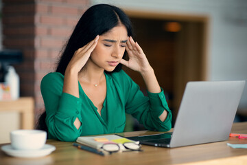 Stressed young arabic woman using laptop at cafe