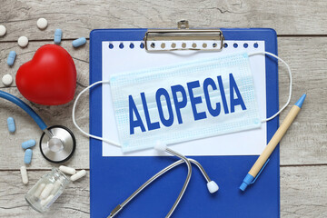 ALOPECIA. Stethoscope with notepad, red heart and pen on blue wooden table