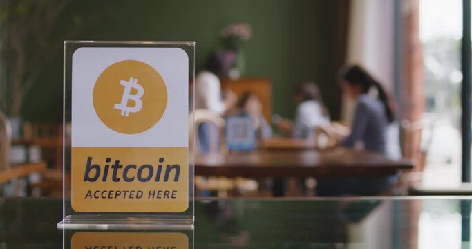 Cryptocurrency Bitcoin ethereum blockchain accepted sign logo on modern SME coffee shop table with defocus blurred background of customer eating enjoy meal. Virtual shopping digital money service.