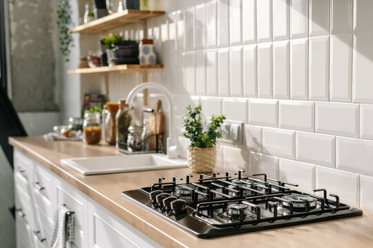 Kitchen in white tones with stove, sink and shelves