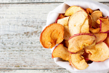 A pile of dried slices of apples in white pouch on wooden background. Dried fruit chips. Healthy food