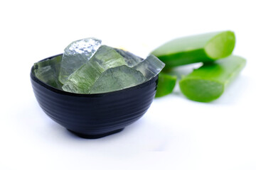 Close-up of organic green fresh aloe vera transparent gel in bowl, isolated over white, light passes through transparent gel, skincare product, Aloe vera cut into small pieces.