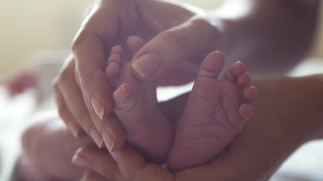 Close-up feet of a nursing baby who has recently been born. Newborn infant boy at home. Window light.