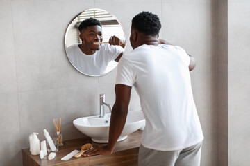 African Man Cleaning Teeth In Morning Using Toothbrush In Bathroom