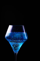 Blue drink is poured into a glass. Black background.