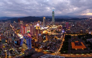 Obraz premium Aerial panorama of Downtown Taipei at dusk, the vibrant capital of Taiwan, with 101 Tower standing out among skyscrapers in Xinyi Commercial District and city lights dazzling under blue twilight sky