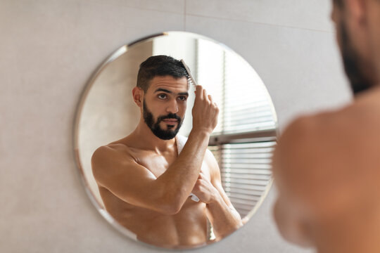 Back Rear View Of Guy Looking In Mirror Brushing Hair