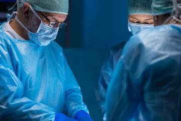 Multiracial team of professional medical surgeons performs the surgical operation in a modern...