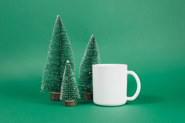 Christmas mock up of white mug on green background with christmas trees.