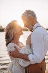 Happy elderly couple in wedding dress looking at each other in sun.