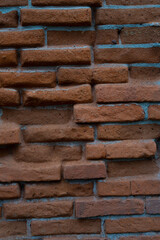 Old red brick wall. The brick is very worn and mutilated over time.