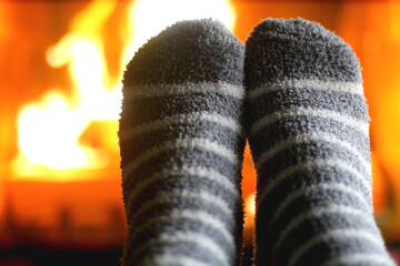 Feet in warm gray socks in front of a fireplace. Selective focus.