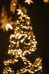 christmas tree with golden lights on black as a bokeh background. Blurred bokeh christams lights. Depth of field.