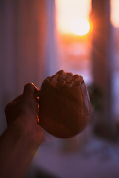hand holding a cup of coca with marshmallows watching sunset at home from the window. Relaxing peaceful moment.