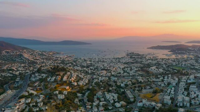 Scenic aerial view of Turkey Bodrum resort town, many houses, harbor full of boats, ships and yachts, ancient Castle of St. Peter, seashore of Aegean sea during beautiful sunset, drone view