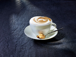 Cappuccino mit Löffel und Amarettini auf Granituntergrund
