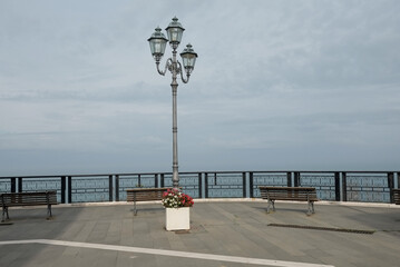 panorama with isolated iron lamppost and railing with benches