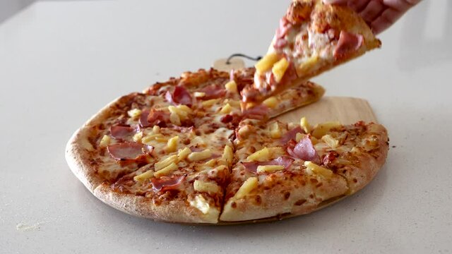 Grabbing a Slice of Hawaiian Pizza with Ham and Pineapple