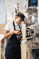 Beautiful and happy young female worker working in a bakery or fast food restaurant and using...