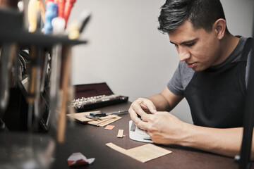 Top view of a man's hands cutting a sheet of cork.