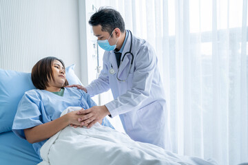 Asian male doctor Caring for a female patient who is lying in hospital