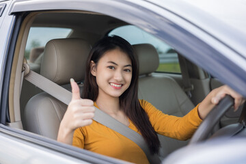 Wow. Young beautiful asian women getting new car. she very happy and excited. she sit and touching every detail of car. Smiling female driving vehicle on the road showing thumb up