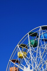 Colorful fair ferris wheel over a blue sky on a sunny day.