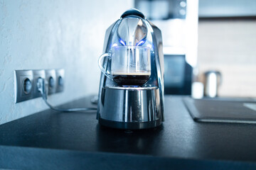 Modern professional espresso coffee machine, cup on kitchen table. Having breakfast in the morning