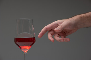 Caucasian male hand reaching out to grab a tall wine glass half full. Studio shot, no people