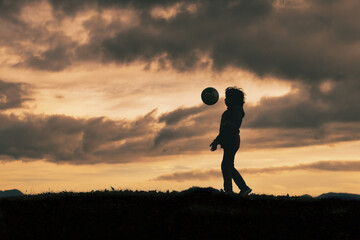 Child in silhouette dribbles with soccer