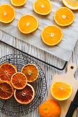 Slices of dry and fresh orange fruits on grid on white table, flat lay