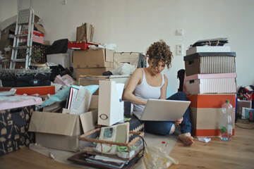 woman organizes boxes and works with pc during a move