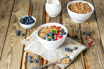 Healthy lifestyle in a breakfast plate with muesli and a spoon on the background of a brown wooden table with milk, berries and orange juice. organic muesli, morning diet for health concept
