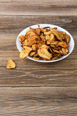 A pile of dried pears in slices on a white plate on wooden background. Dried fruit chips. Healthy food