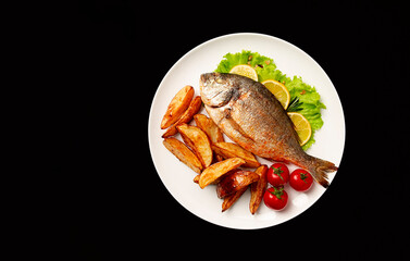 Fried Dorado fish, with potatoes, top view, on a black background, no people,