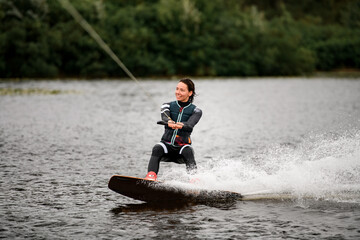 Obraz premium sportive woman wakeboarding on board on the river water on summer day